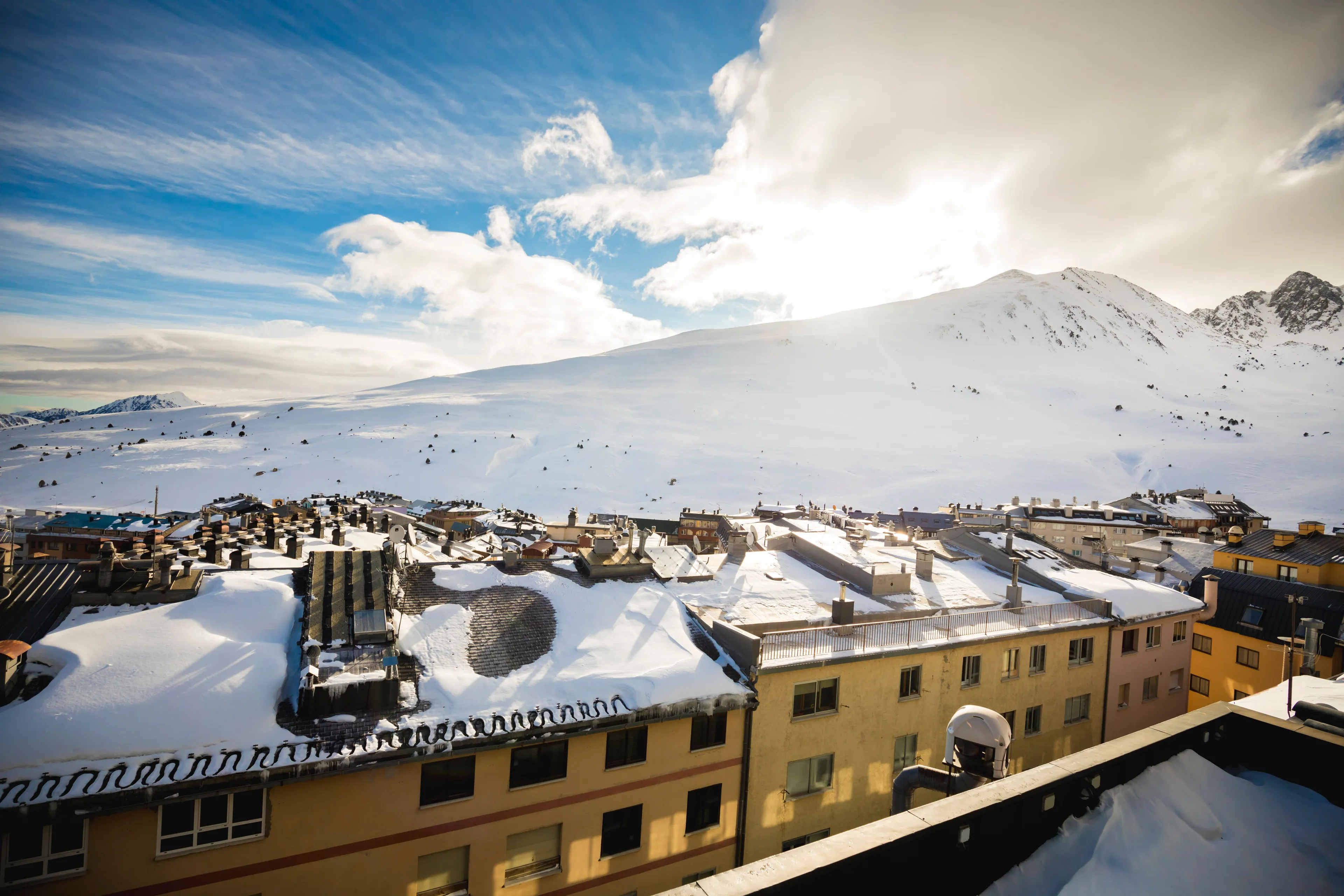 Fasad av Font D’Argent Pas de la Casa med snöklädda berg i bakgrunden