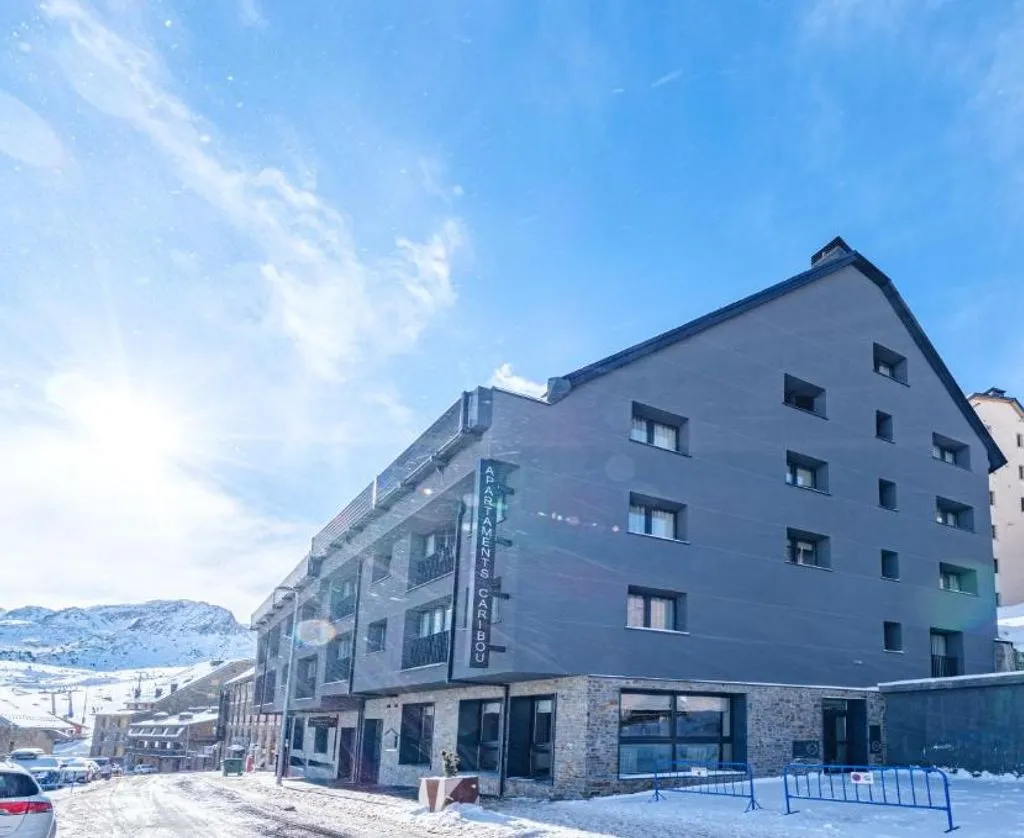 Vy över Caribou Apartments med snötäckta berg i bakgrunden i Pas de la Casa, Andorra